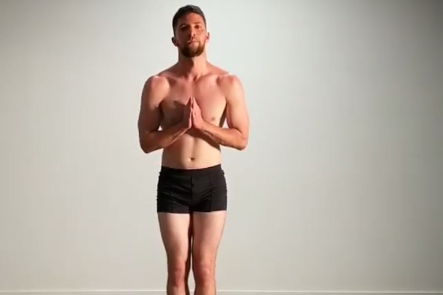 A man in underwear, with no shirt on, bows.