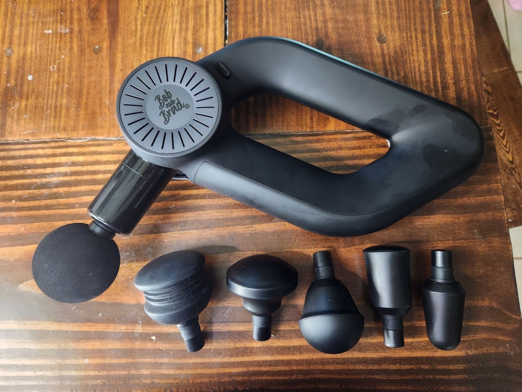 massage gun laid out on tablet with six interchangeable attachments